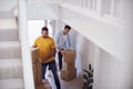 Excited Male Couple Carrying Boxes Through Front Door Of New Home On Moving Day Royalty Free Stock Photo