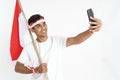 Excited male holding indonesian flag and taking selfie