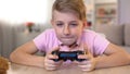 Excited male kid playing video game with console, eyesight problems risk