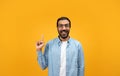 An excited man with a beard and glasses raises his index finger, sporting a bright smile Royalty Free Stock Photo
