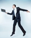 Excited man of business jumping with laptop over background