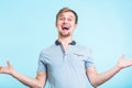 Excited man exclaimed in happiness, gestures actively, expressed great surprisement, over blue background