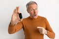 Excited Man Holding Car Key And Pointing, White Background Royalty Free Stock Photo