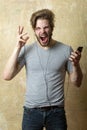 Excited man listening music with smartphone. Surprised male with phone and earphones. Emotional portrait guy. Royalty Free Stock Photo