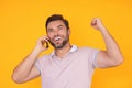 Excited man in t-shirt using mobile phone isolated on studio background. Portrait of confidence middle aged millennial Royalty Free Stock Photo