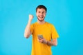 Excited man using mobile phone at studio, celebrating online win Royalty Free Stock Photo