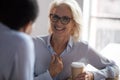 Excited mature businesswoman talking with colleague during coffee break