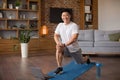 Excited mature korean man doing lunges, exercising for legs in living room interior, looking at camera and smiling Royalty Free Stock Photo