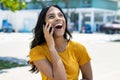 Excited mexican young adult woman talking with boyfriend at phone Royalty Free Stock Photo