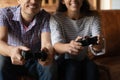 Excited millennial couple dating indoors holding joypads playing console game
