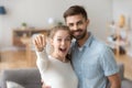 Excited millennial couple holding key to new house