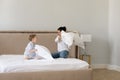 Excited mom and active little son pillow fighting on bed