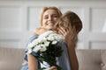 Excited mommy hugging little daughter receiving flowers on Mothers Day Royalty Free Stock Photo