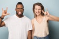 Excited multiethnic man and woman show rock-n-roll hand gesture