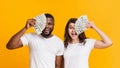 Excited multiracial couple covering eyes with dollar cash fan