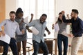 Overjoyed multiethnic employees dancing at workplace celebrating work success Royalty Free Stock Photo