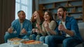 Excited people sport fans watch football at home celebrating win goal soccer match game at living room. Happy diverse Royalty Free Stock Photo