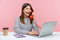 Excited positive secretary in striped shirt making calls on landline telephone working on laptop sitting at office, looking at Royalty Free Stock Photo