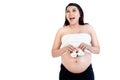 Excited pregnant woman holding pair of baby shoes over her belly