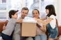 Excited kids unpack cardboard box shopping with parents online Royalty Free Stock Photo