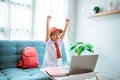 excited primary school student with uniform raise her arm during online class