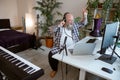 Excited professional presenter conducts podcast showing peace gesture in home studio Royalty Free Stock Photo