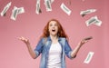 Excited redhead girl standing under money shower Royalty Free Stock Photo