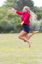 Excited 20s woman jumping high with fun in sunny park Royalty Free Stock Photo