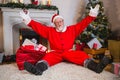 Excited santa claus sitting on rug in living room