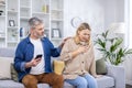 Excited scared man is calling an ambulance on the phone because his wife is sick, she is holding her heart with her hand Royalty Free Stock Photo