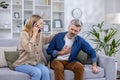 Excited scared wife is calling an ambulance on the phone because her husband is sick, he is holding his hand to his Royalty Free Stock Photo