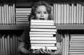 Excited school kid hold stack of books. Surprised school kid. Schoolboy reading book in library. Kids learn to read Royalty Free Stock Photo