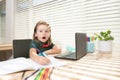 Excited schoolboy does homework in school class. Writes text from laptop notebook. Royalty Free Stock Photo