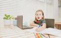 Excited schoolboy does homework in school class. Writes text from laptop notebook. Royalty Free Stock Photo