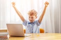 Excited schoolboy learning online on laptop