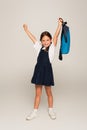 excited schoolkid with blue backpack showing