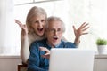 Excited senior couple looking at laptop surprised by good news