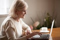 Excited senior lady browsing web using laptop at home Royalty Free Stock Photo