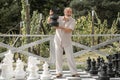 Excited senior playing chess on big chessboard in the park. Chess game for old man. Older grandfather, grandpa pensioner Royalty Free Stock Photo