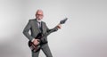 Excited senior rock musician in suit singing with mouth open and playing guitar on white background Royalty Free Stock Photo