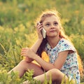 Excited serious cute kid girl sitting on the glass, talking on m