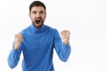 Excited, serious-looking intense young man placed bet on football sport match, clench fists and shouting rooting for Royalty Free Stock Photo