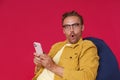 Excited, shocked handsome man in eye glasses hold smartphone in hands looking at camera with WOW look wearing yellow Royalty Free Stock Photo