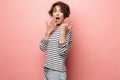Excited shocked surprised beautiful woman posing isolated over pink wall background pointing