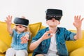 excited siblings using virtual reality headset and sitting