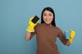 Excited smiling asian young housemaid holding a sponge and coffee cup Royalty Free Stock Photo