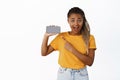 Excited smiling black girl pointing finger at smartphone screen, showing mobile phone app interface, recommending Royalty Free Stock Photo