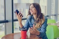 Excited smiling happy woman having a rest in a cafe, she is looking at screen of her smartphone telephone mobile phone sms notific Royalty Free Stock Photo