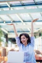 Excited smiling woman celebrating online win, using laptop in cafe, looking at screen, screaming with raising hands. Royalty Free Stock Photo