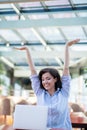 Excited smiling woman celebrating online win, using laptop in cafe, looking at screen, screaming with raising hands. Royalty Free Stock Photo